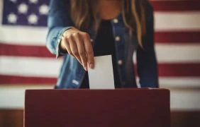 Aufnahme einer Frau, die ihren Stimmzettel in die Wahlurne wirft.