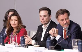 Elon Musk zwischen britischen Regierungsvertretern.