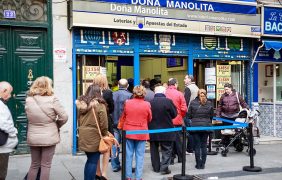 Menschen warten vor einem spanischen Lottoladen.
