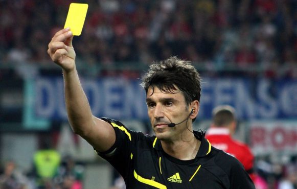 Aufnahme eines Schiedsrichters, der einem Spieler die Gelbe Karte zeigt.