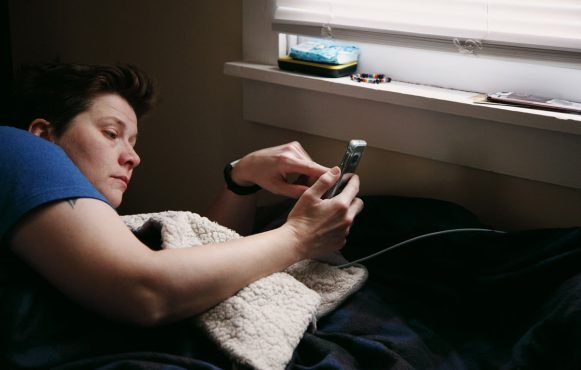 Eine Frau schaut müde auf ihr Handy