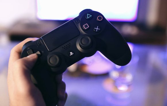 Person mit PlayStation-Controller in der Hand.