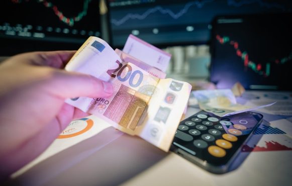 Ein Mann hält 200 Euro am Schreibtisch in der Hand