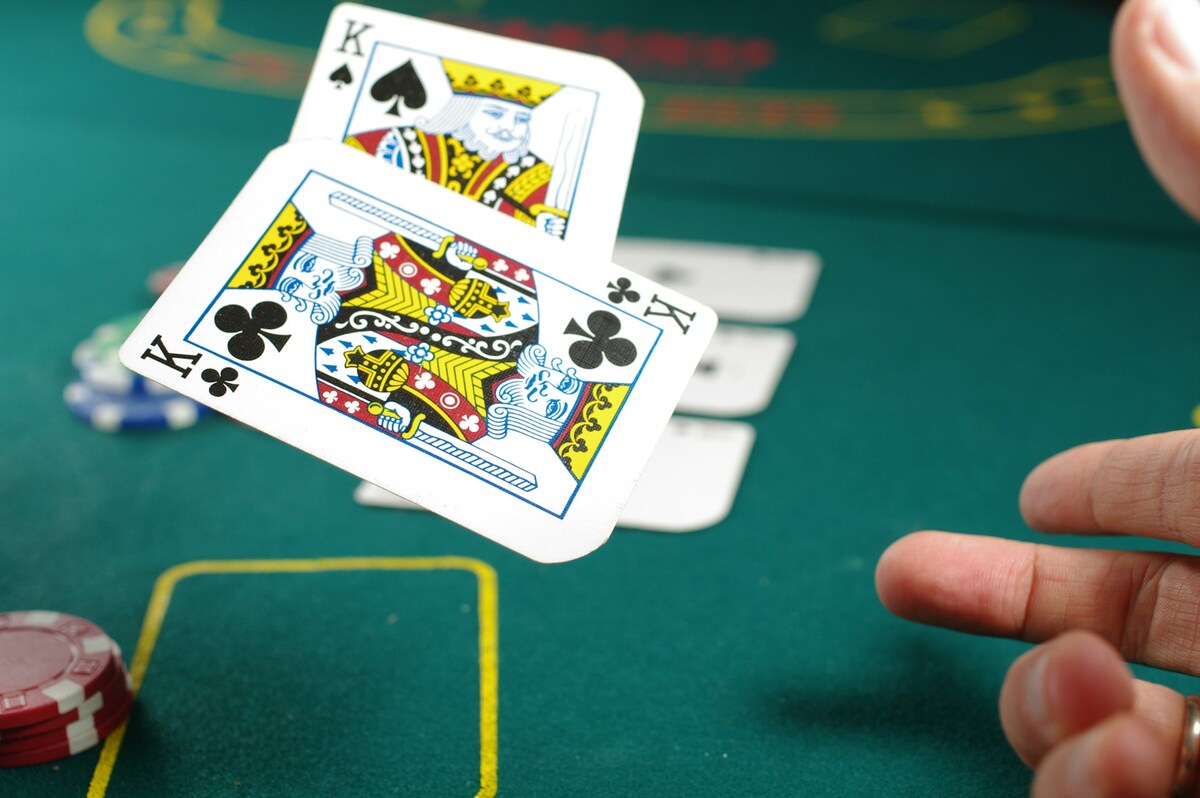 Person wirft Pokerkarten auf Pokertisch.