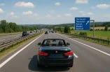 Ein schwarzes Cabrio mit zwei Personen fährt an einem sonnigen Tag auf der deutschen Autobahn.