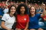 Drei Frauen in Fußball-Trikots, die sich in einem Fußballstadion in den Armen liegen.