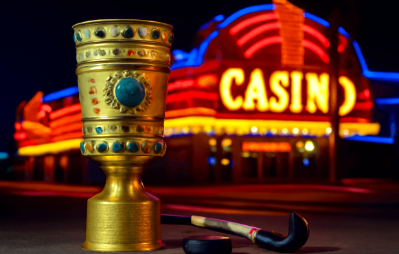 Ein leuchtendes Casino, davor der DFB-Pokal und ein Hockeyschläger samt Puck.