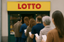 Vor einer Lotto-Annahmestelle hat sich eine Schlange von Menschen gebildet.