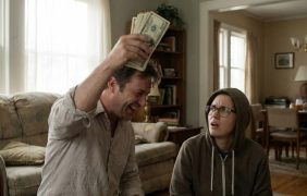 Ein Mann hält jubelnd ein Bündel Geldscheine in die Höhe, während eine weitere Person neben ihm überrascht und fragend auf ihn blickt.