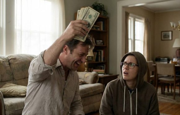 Ein Mann hält jubelnd ein Bündel Geldscheine in die Höhe, während eine weitere Person neben ihm überrascht und fragend auf ihn blickt.