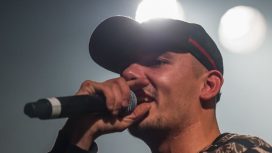 Capital Bra mit einem Mikrofon in der Hand bei einem Konzert.