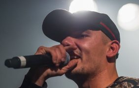 Capital Bra mit einem Mikrofon in der Hand bei einem Konzert.