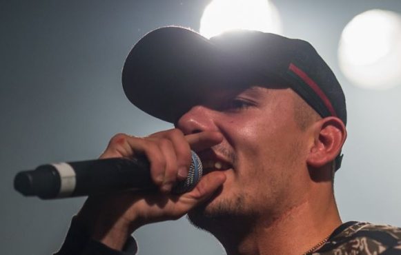 Capital Bra mit einem Mikrofon in der Hand bei einem Konzert.