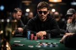 Ein Mann sitzt an einem Pokertisch und hat eine Sonnenbrille auf.