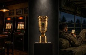 Zwei Spielautomaten in einer Kneipe, der DFB-Pokal und ein Soldat spielt Slots auf seinem Smartphone.