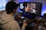 Ein Mann schaut einen Livestream, in dem Trading Cards geöffnet werden. Vor ihm liegen verschiedene Stapel mit Trading Cards.