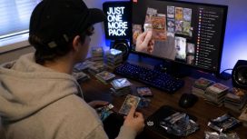 Ein Mann schaut einen Livestream, in dem Trading Cards geöffnet werden. Vor ihm liegen verschiedene Stapel mit Trading Cards.