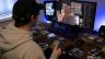 Ein Mann schaut einen Livestream, in dem Trading Cards geöffnet werden. Vor ihm liegen verschiedene Stapel mit Trading Cards.