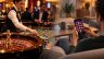 Auf der linken Seite sehen wir eine Croupière in einem Casino an einem Blackjack-Tisch. Rechts sitzt ein Mann auf seiner Couch und spielt auf seinem Handy an einem Slot-Automaten.